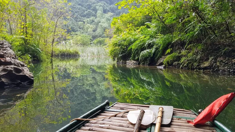 Uitzicht vanaf de punt van een roeibootje over het spiegelgladde water in Ninh Binh